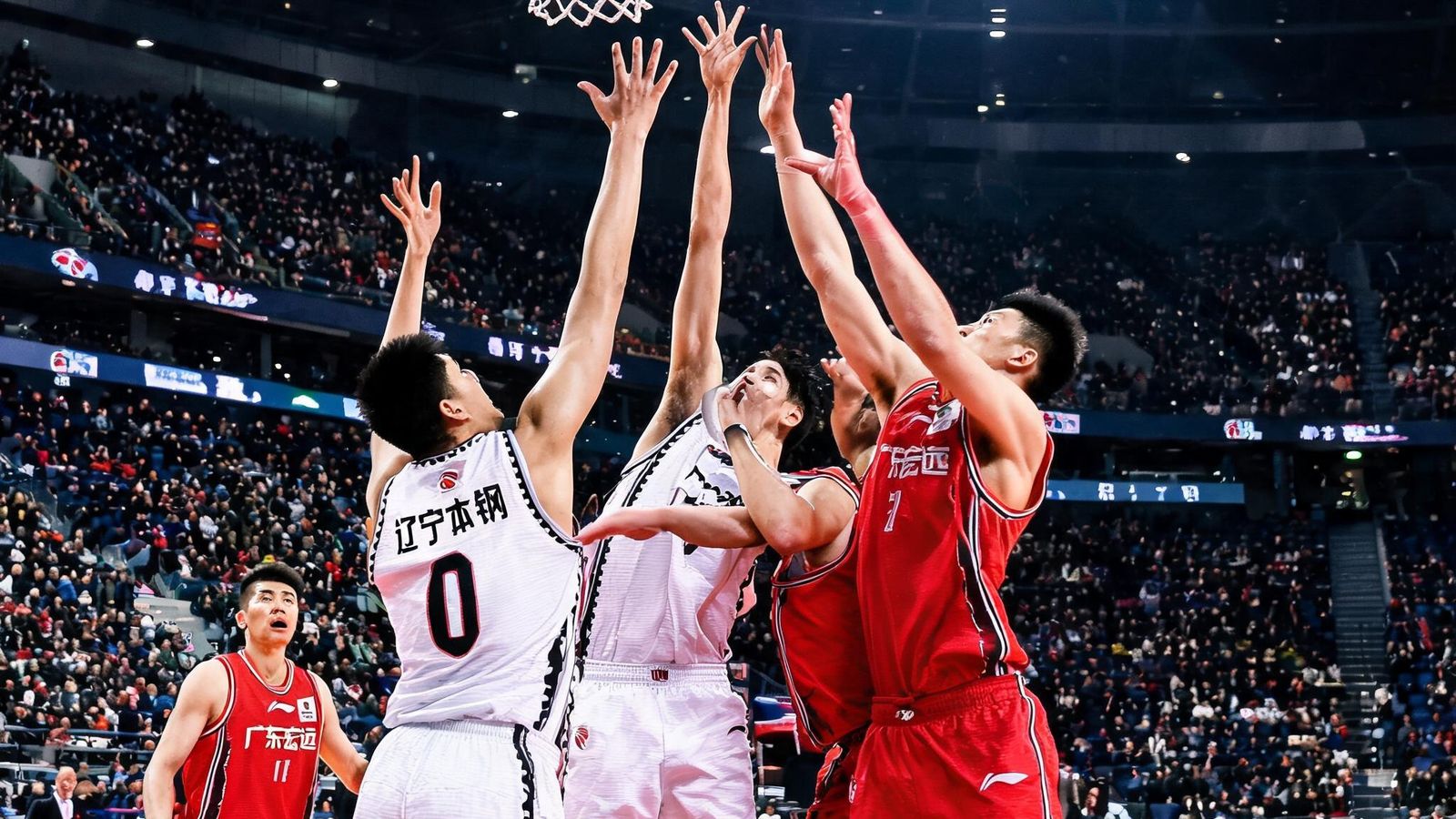 CBA辽宁本钢队与广东宏远队球员在赛场上激烈争抢篮板球的瞬间，体育馆内座无虚席